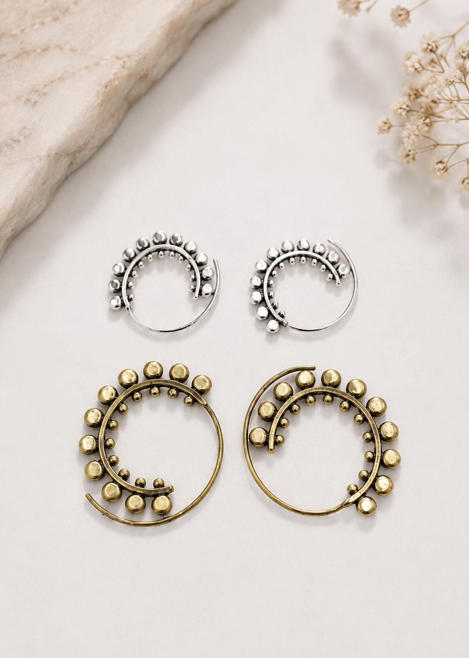 Orecchini a spirale con sfere decorative nelle varianti ottone e argentata.
