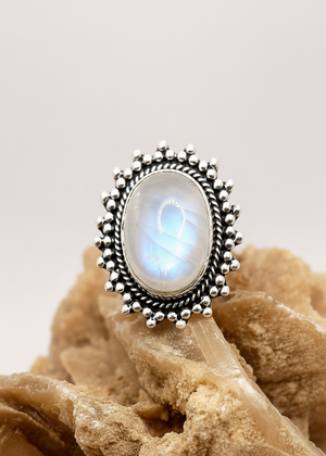 Anello in argento con pietra di luna naturale iridescente su cristallo color sabbia
