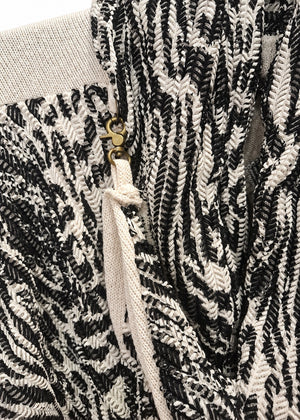 Dettaglio del gancio laterale della Cross Jacket bianca, con chiusura a moschettone, asola in cotone e tessuto a fantasia nera