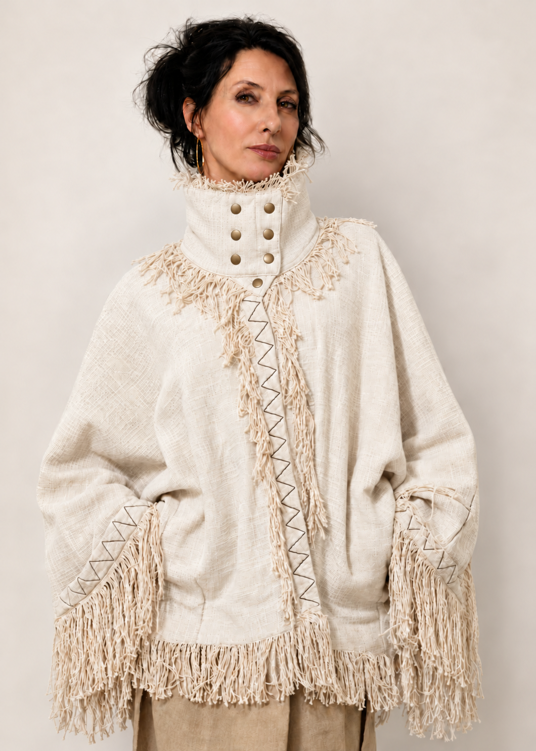 Fringe Poncho bianco in 100% cotone indossato, con collo alto strutturato, bottoni e frange.