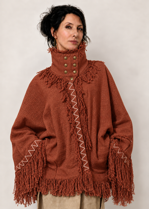 Fringe Poncho Terracotta in 100% cotone indossato, con collo strutturato, sette bottoni e frange.