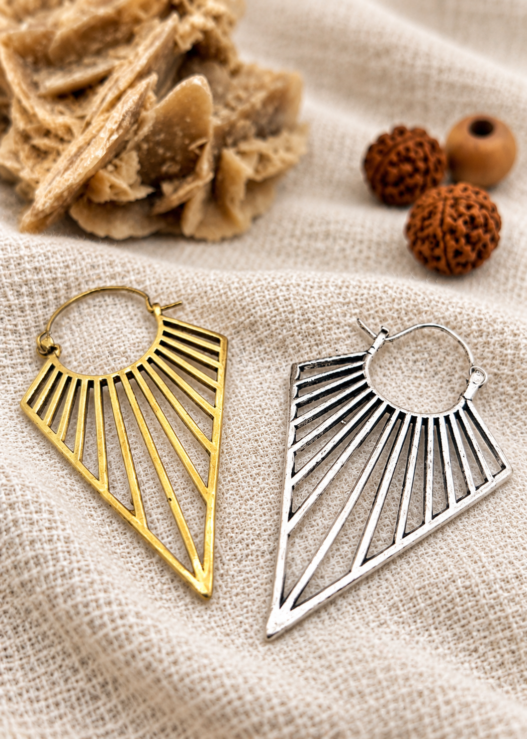 Orecchini triangolari Nomad Light nelle finiture ottone e bagno d’argento su juta chiara