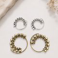 Orecchini a spirale con sfere decorative nelle varianti ottone e argentata.