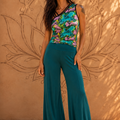 Donna con pantalone palazzo verde petrolio e top asimmetrico a stampa floreale multicolore