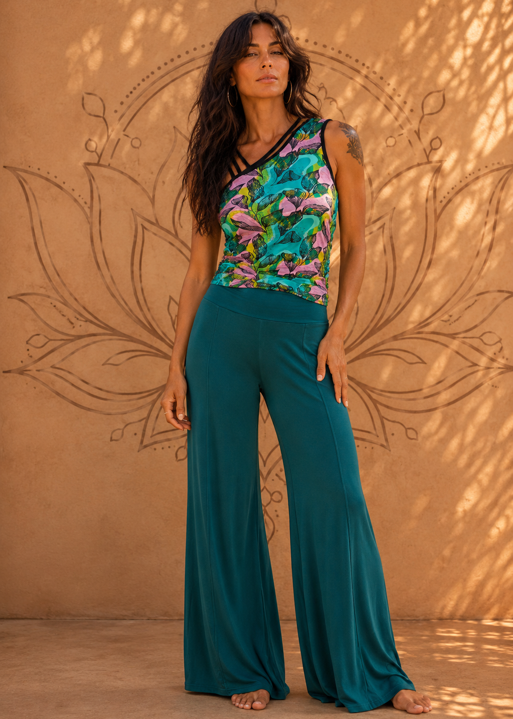 Donna con pantalone palazzo verde petrolio e top asimmetrico a stampa floreale multicolore