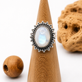 Anello in argento con pietra di luna ovale iridescente su espositore in legno