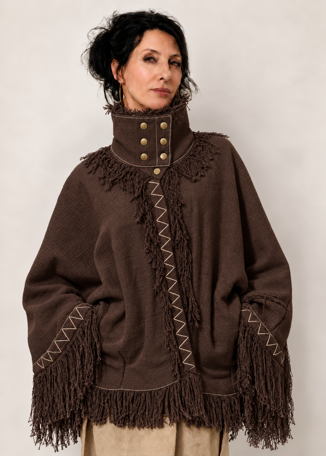 Fringe Poncho Marrone scuro in 100% cotone indossato, con collo strutturato, sette bottoni e frange.