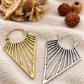 Orecchini triangolari Nomad Light nelle finiture ottone e bagno d’argento su juta chiara